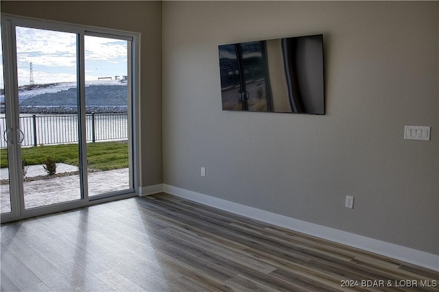 spare room with wood-type flooring and a water view