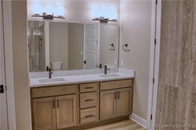 bathroom featuring hardwood / wood-style flooring, vanity, toilet, and a shower