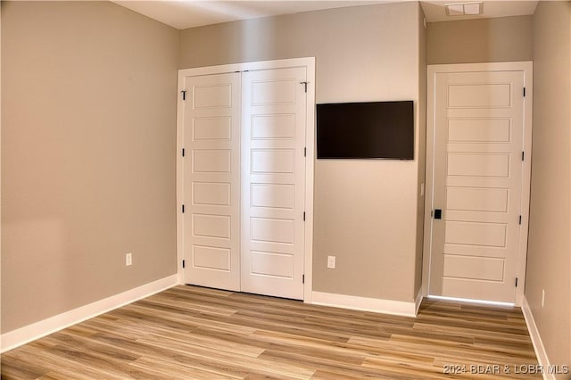 unfurnished bedroom with light hardwood / wood-style flooring and a closet