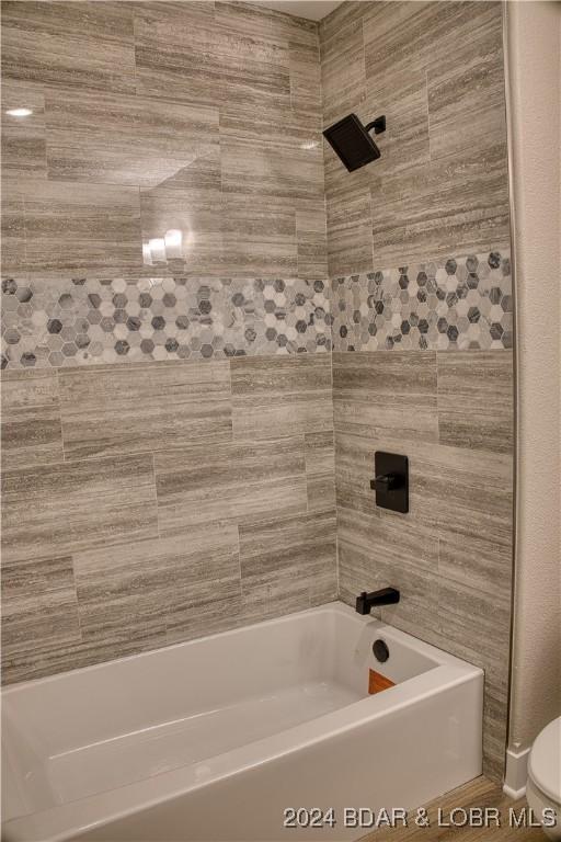 bathroom featuring tiled shower / bath and toilet