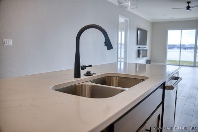 kitchen featuring sink, light stone counters, wood-type flooring, stainless steel dishwasher, and ornamental molding