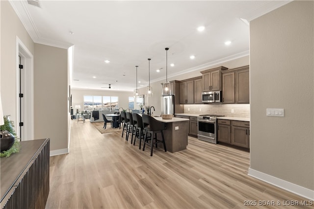 kitchen with stainless steel appliances, a kitchen bar, open floor plan, and ornamental molding