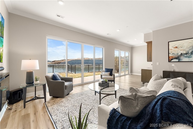 living room featuring visible vents, baseboards, light wood-style flooring, and crown molding