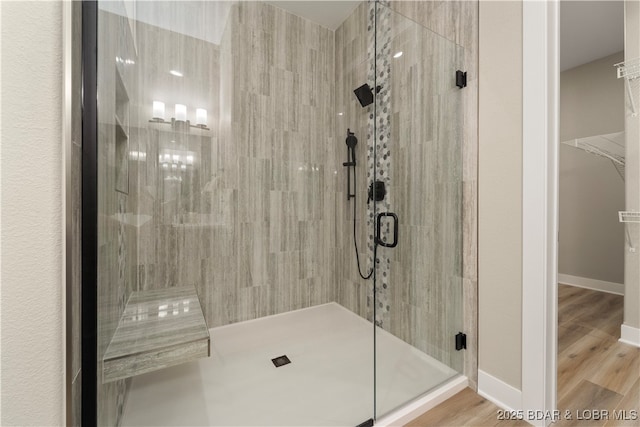 bathroom featuring a shower stall, baseboards, and wood finished floors