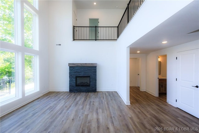 17023 Seminole Dr W, Rocky Mount, MO 65072 - unfurnished living room featuring a high ceiling, healthy amount of natural light, wood finished floors, a fireplace, and recessed lighting