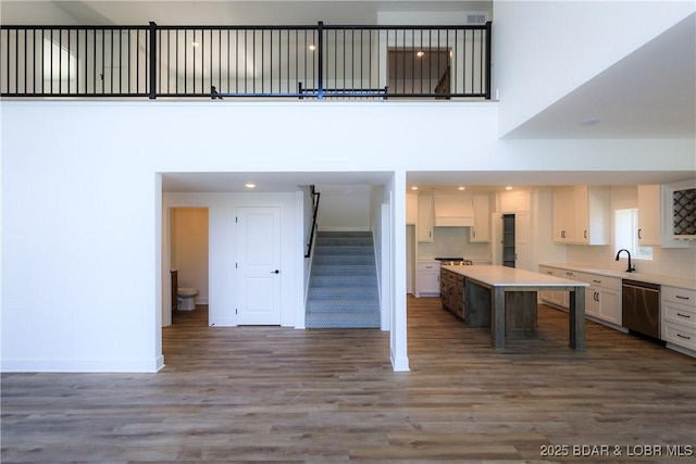 17023 Seminole Dr W, Rocky Mount, MO 65072 - kitchen with stainless steel dishwasher, wood finished floors, white cabinets, light countertops, and tasteful backsplash