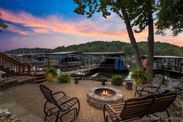 patio terrace at dusk featuring a fire pit and a dock