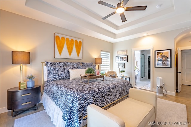 bedroom featuring a raised ceiling, ceiling fan, and hardwood / wood-style floors