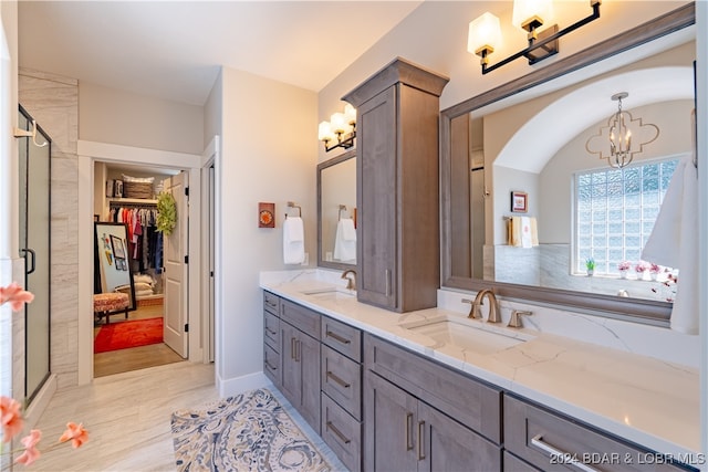 bathroom featuring a shower with shower door, a notable chandelier, and vanity