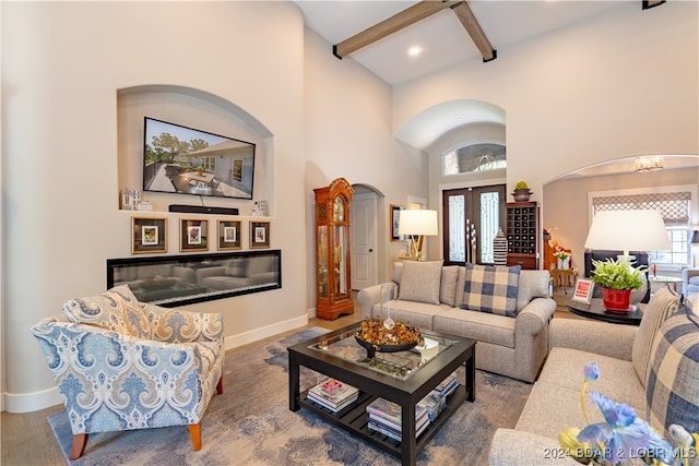 living room featuring a high ceiling, hardwood / wood-style flooring, beamed ceiling, and french doors