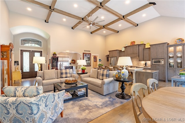 living room featuring light hardwood / wood-style flooring, ceiling fan, a towering ceiling, and french doors