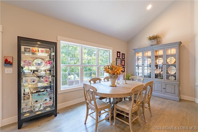 dining room with high vaulted ceiling and light wood-type flooring