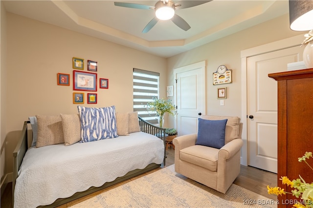 bedroom featuring a tray ceiling, wood-type flooring, and ceiling fan