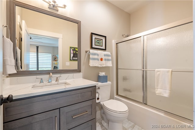 full bathroom featuring ceiling fan, toilet, combined bath / shower with glass door, and vanity