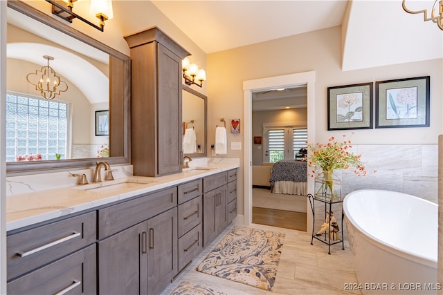 bathroom with vanity, tile walls, a bathing tub, and a notable chandelier