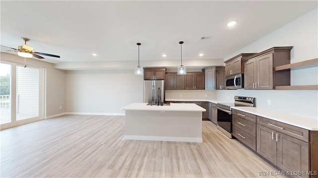 kitchen featuring ceiling fan, stainless steel appliances, pendant lighting, light hardwood / wood-style floors, and a center island