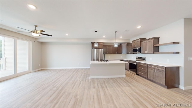 kitchen with a kitchen island, ceiling fan, stainless steel appliances, pendant lighting, and light hardwood / wood-style flooring