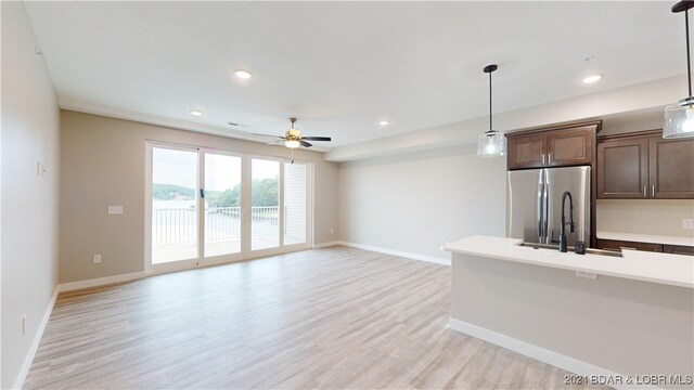 unfurnished living room with light hardwood / wood-style floors, sink, and ceiling fan