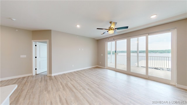 spare room featuring a water view, light wood-type flooring, and ceiling fan