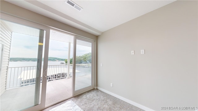 doorway to outside with light carpet and a water view