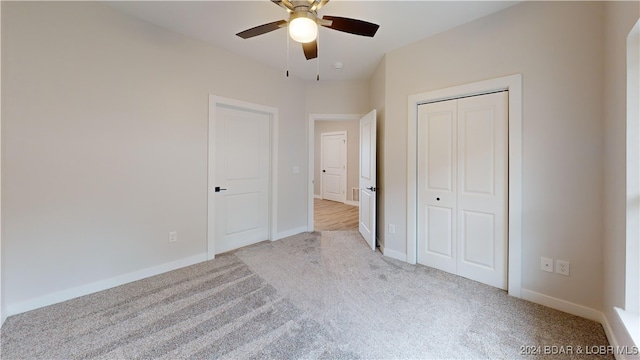 unfurnished bedroom featuring light carpet, a closet, and ceiling fan