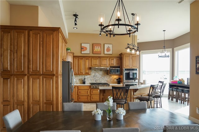 kitchen featuring hanging light fixtures, appliances with stainless steel finishes, a notable chandelier, track lighting, and tasteful backsplash