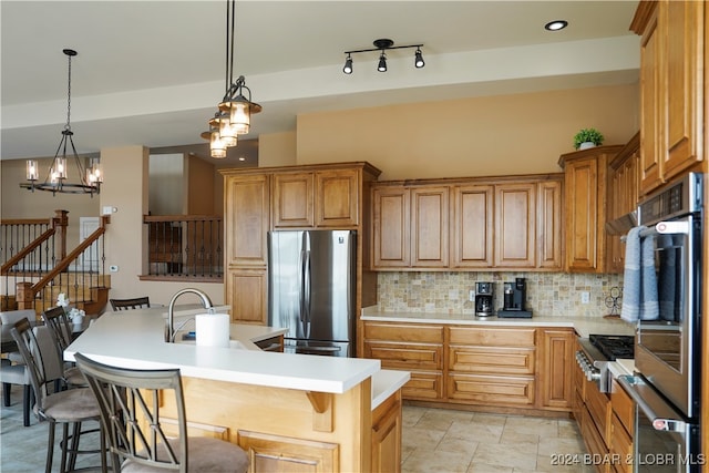 kitchen featuring a chandelier, decorative light fixtures, an island with sink, a breakfast bar, and appliances with stainless steel finishes