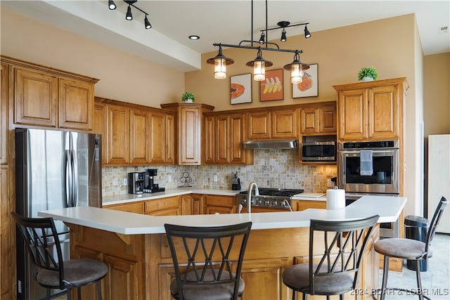 kitchen featuring an island with sink, rail lighting, stainless steel appliances, and a kitchen bar