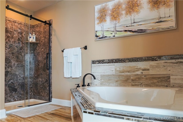 bathroom featuring wood-type flooring and shower with separate bathtub