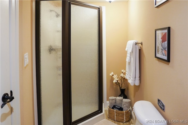 bathroom with toilet and a shower with shower door