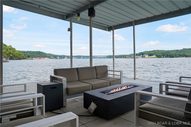 dock area with a water view, a patio area, and an outdoor living space with a fire pit