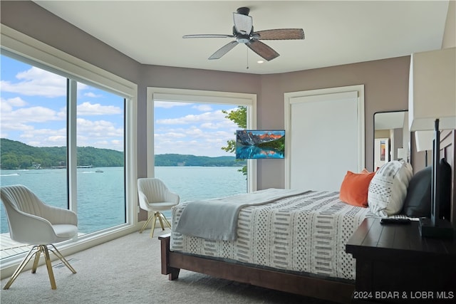 carpeted bedroom featuring a water view, ceiling fan, and access to outside