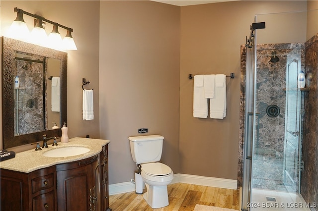 bathroom featuring a shower with shower door, toilet, vanity, and hardwood / wood-style flooring