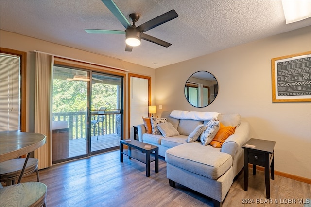 living room featuring ceiling fan, wood-type flooring, and a textured ceiling