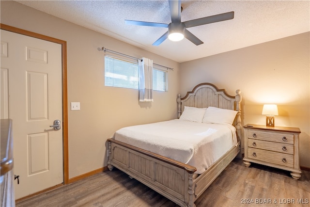 bedroom featuring a ceiling fan, a textured ceiling, baseboards, and wood finished floors