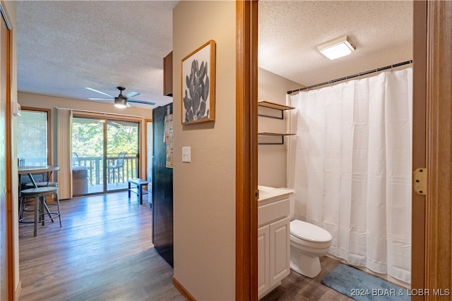 bathroom featuring a textured ceiling, toilet, wood finished floors, vanity, and a ceiling fan