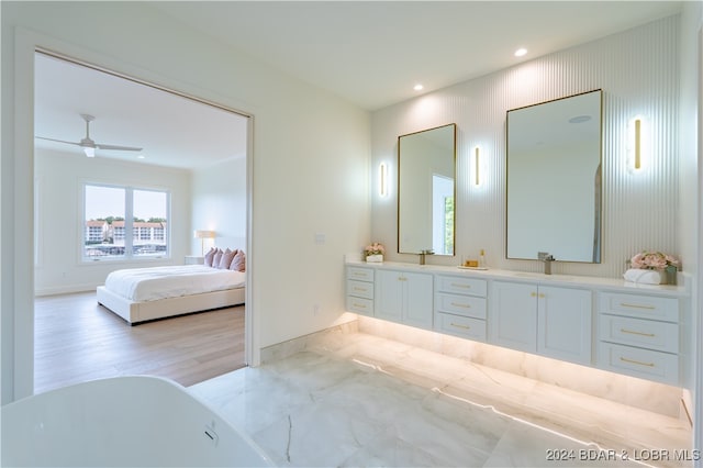 bathroom with wood-type flooring, ceiling fan, a tub, and vanity