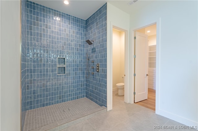 bathroom featuring a tile shower, toilet, and tile patterned floors