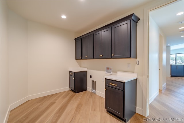 bar with light wood-type flooring and dark brown cabinetry