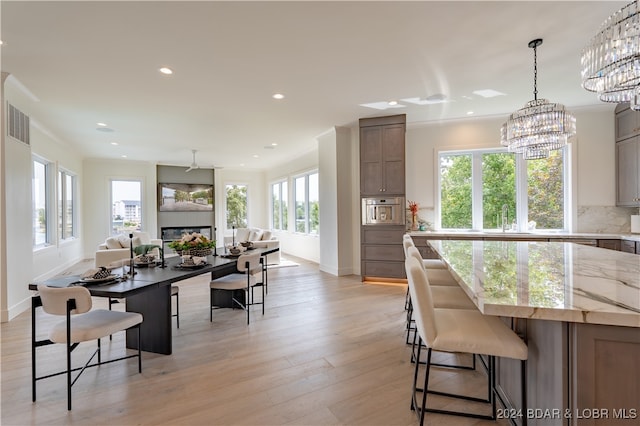 kitchen with light wood-type flooring, plenty of natural light, a kitchen breakfast bar, and decorative backsplash