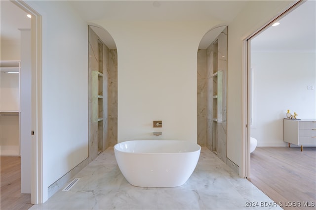 bathroom with a tub to relax in and wood-type flooring