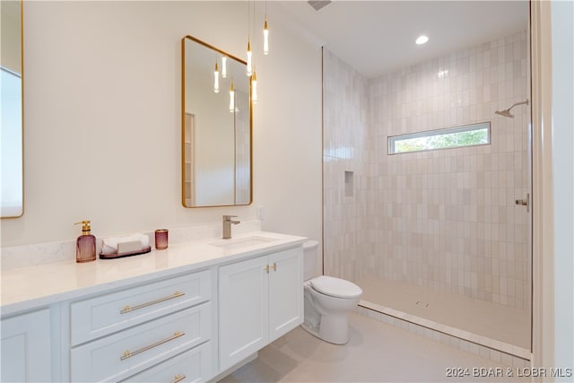 bathroom with a tile shower, vanity, and toilet