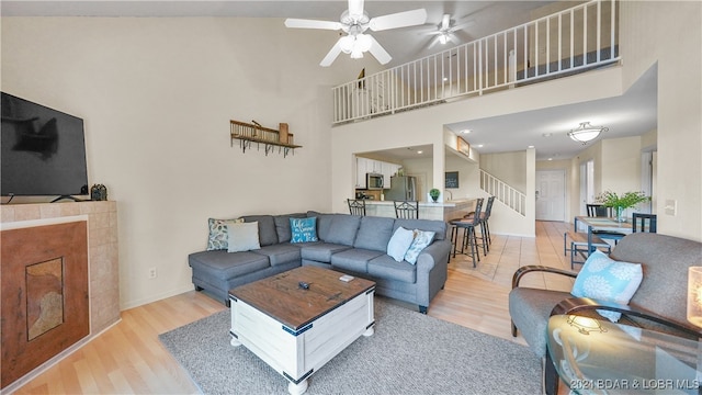 living room with light wood-type flooring, ceiling fan, and high vaulted ceiling