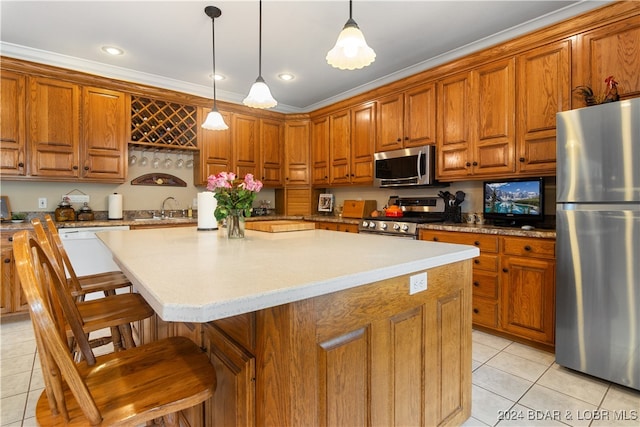 kitchen featuring a kitchen island, a kitchen breakfast bar, appliances with stainless steel finishes, crown molding, and hanging light fixtures