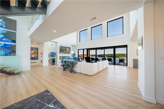 living room with a towering ceiling and light hardwood / wood-style floors