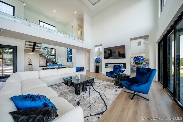 living room featuring light hardwood / wood-style flooring, a high ceiling, and a fireplace