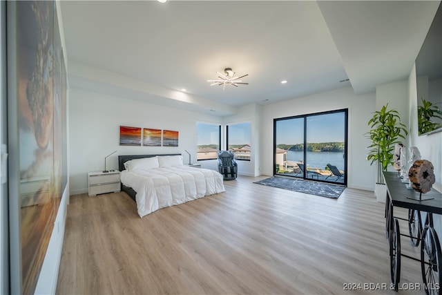 bedroom featuring a water view, access to exterior, and light hardwood / wood-style floors