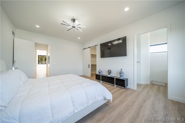 bedroom featuring a barn door and light hardwood / wood-style flooring