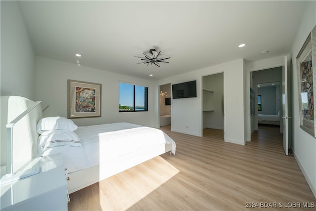 bedroom with connected bathroom, light hardwood / wood-style flooring, a walk in closet, and a closet