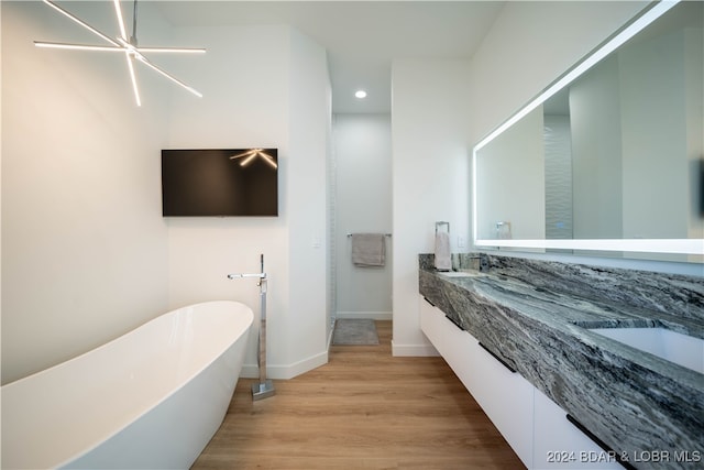 bathroom featuring a tub to relax in, vanity, an inviting chandelier, and hardwood / wood-style flooring